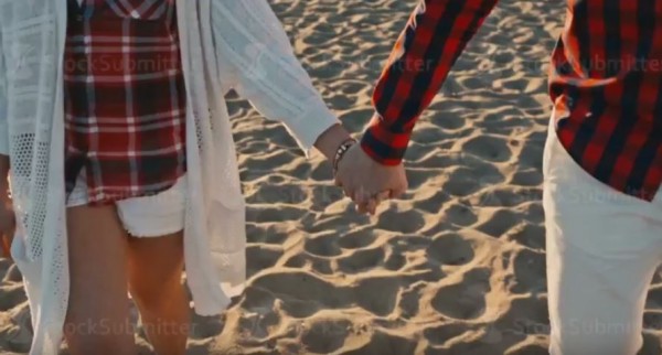 Young Couple holding hands at sunset on beach