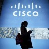 A visitor walks past a Cisco advertising panel as she looks at her mobile phone.