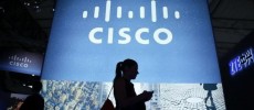 A visitor walks past a Cisco advertising panel as she looks at her mobile phone.