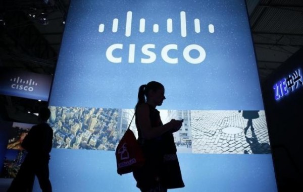 A visitor walks past a Cisco advertising panel as she looks at her mobile phone.