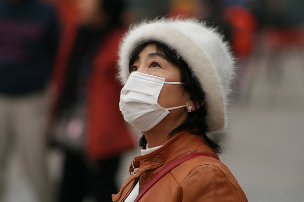 A woman in China covering her face due to dangerous pollution levels that take the lives of 1.6 million citizens each year.