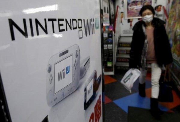 A woman walks past an advertisement board of Nintendo Co Ltd's Wii U game console.