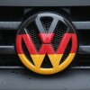 Volkswagen logo and hood ornament in the colors of the German flag is visible on the front grille of a car in Berlin, Germany. 