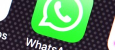 A user's finget is seen over a WhatsApp logo on a smartphone screen.