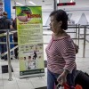  Ferry passengers arriving from Singapore walk near a banner about the Zika virus .