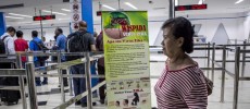  Ferry passengers arriving from Singapore walk near a banner about the Zika virus .