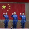 (L-R) Chinese astronauts of the Shenzhou-10 manned spacecraft mission Wang Yaping, Nie Haisheng and Zhang Xiaoguang sit in front of a Chinese national flag as they meet the media at the Jiuquan Satell