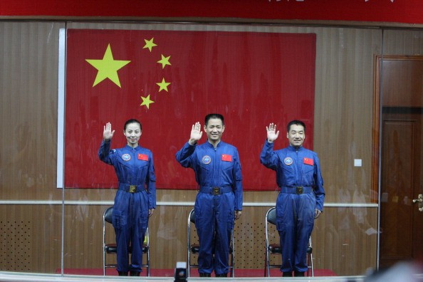 (L-R) Chinese astronauts of the Shenzhou-10 manned spacecraft mission Wang Yaping, Nie Haisheng and Zhang Xiaoguang sit in front of a Chinese national flag as they meet the media at the Jiuquan Satell